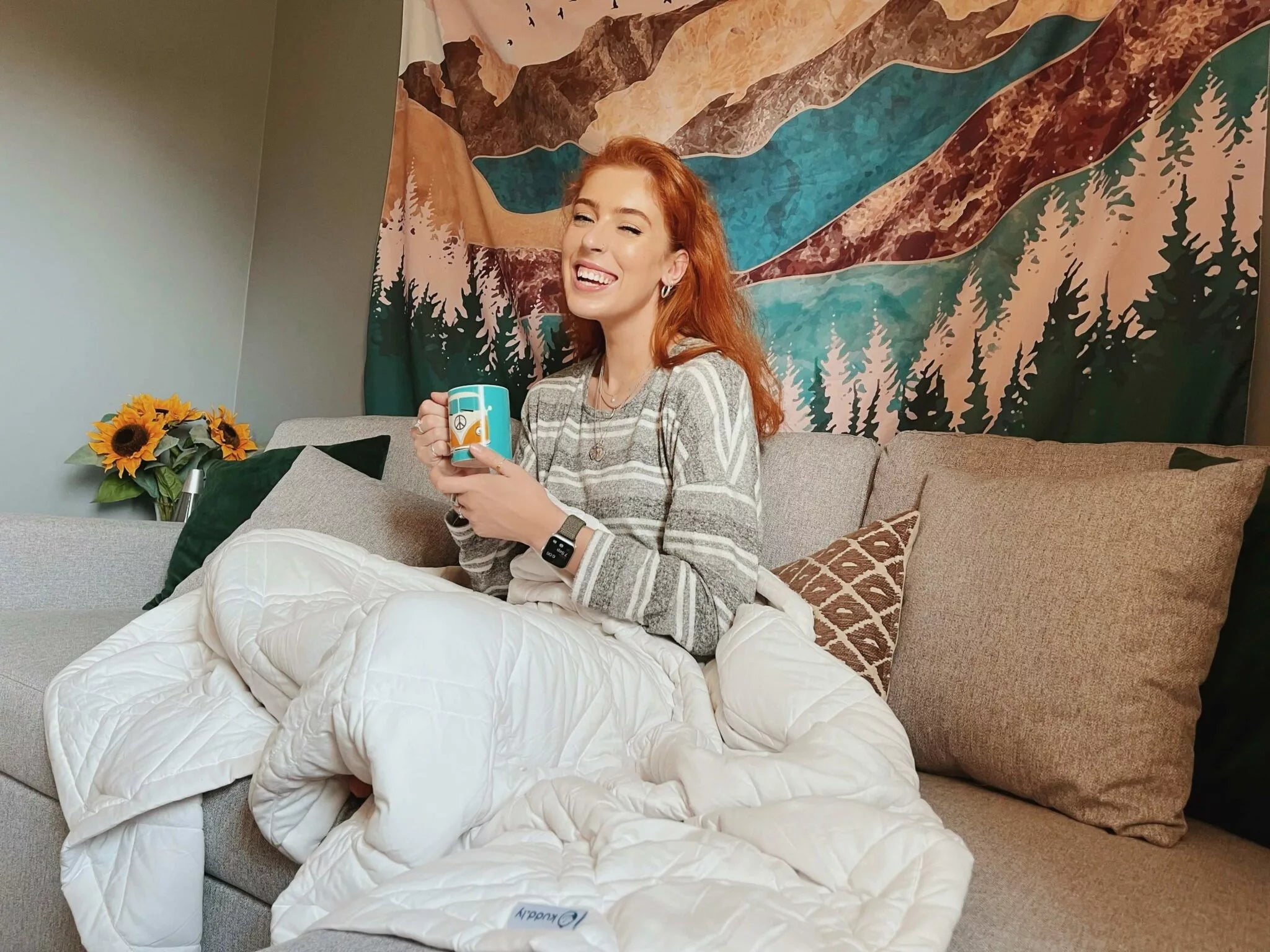 Woman using a cooling weighted blanket holding a mug