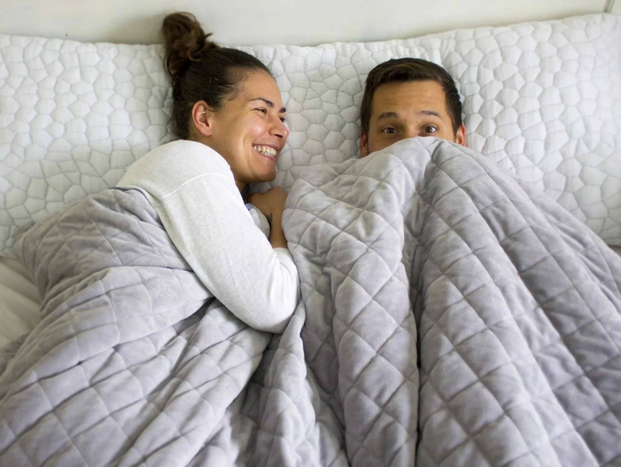 Couple using light grey therapeutic weighted blanket in bed